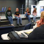 Students performing Frozen Jr. on stage with Arendelle castle backdrop and sparkling snow effects